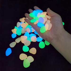 Hand holding multicolored glow in dark garden rocks scattered on black surface, home decor items, lifestyle products, gifts, . - BagnShop - Glow In Dark Garden Rocks (Pack Of 100 pcs) - appliance, shop - Default Title